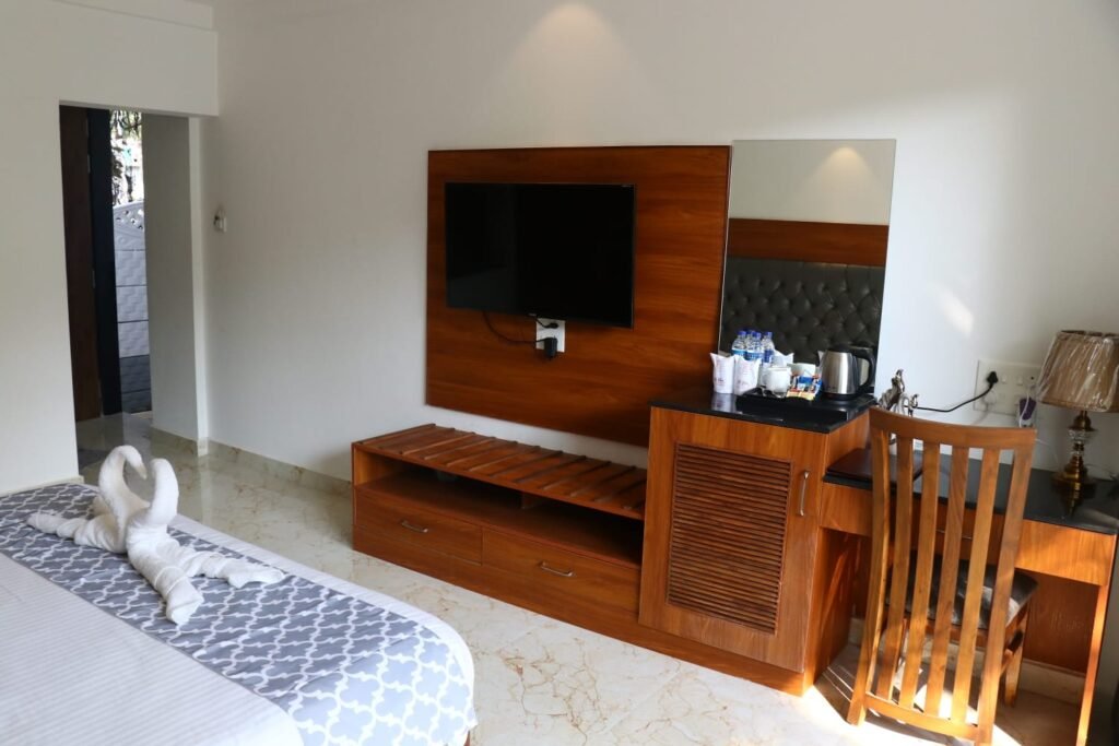 Comfortable hotel room at La Vera Boutique Hotel near Mandrem Beach Goa with cozy bed, TV, wooden furniture, desk, and seating area