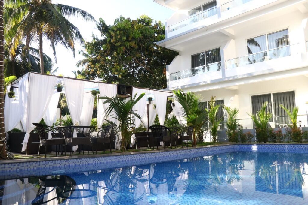 Boutique hotel near Mandrem Beach Goa with swimming pool, outdoor seating, palm trees, and lush tropical surroundings