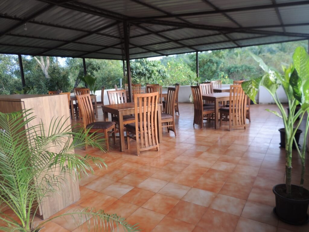 Open-air restaurant near Ashvem Beach Goa with wooden tables, chairs, and lush green surroundings